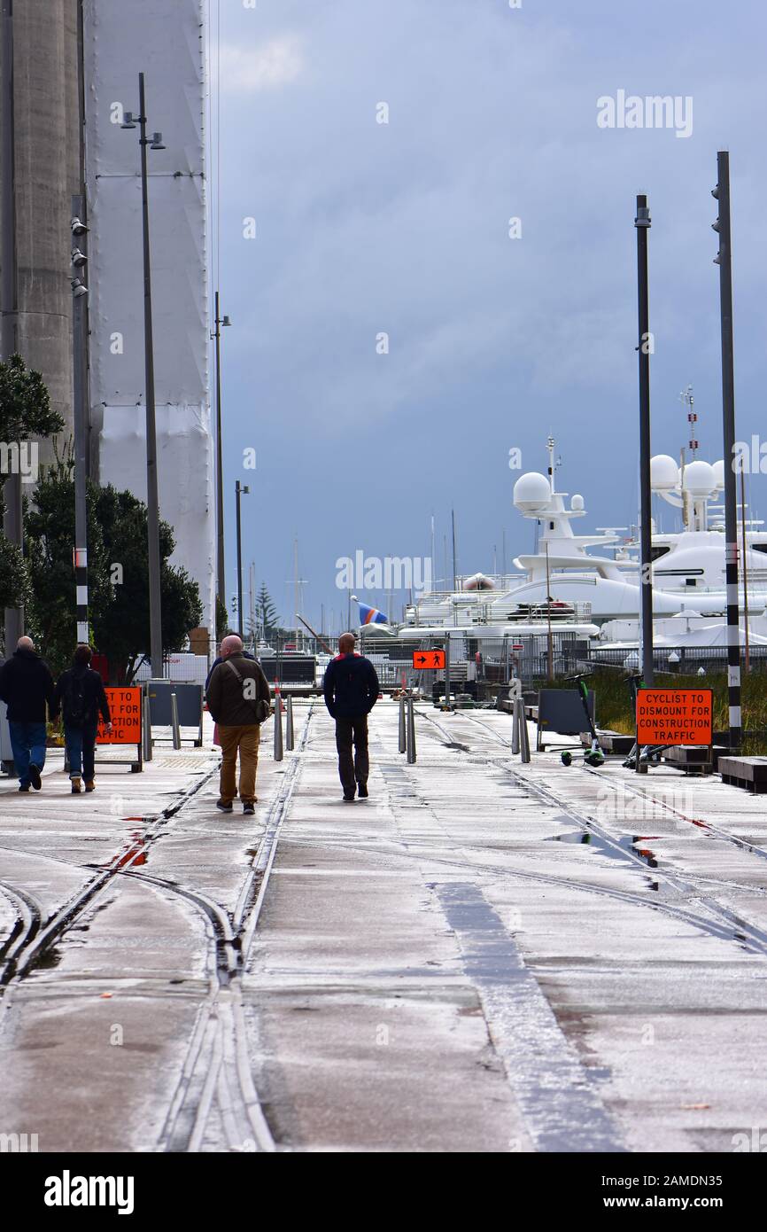 Pedestrian zone in silo park in Auckland with walkway over old railway tracks along concrete silos and luxurious yachts. Stock Photo