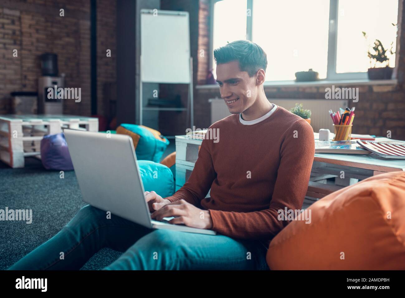 Cheerful handsome freelancer feeling good while working at home Stock Photo