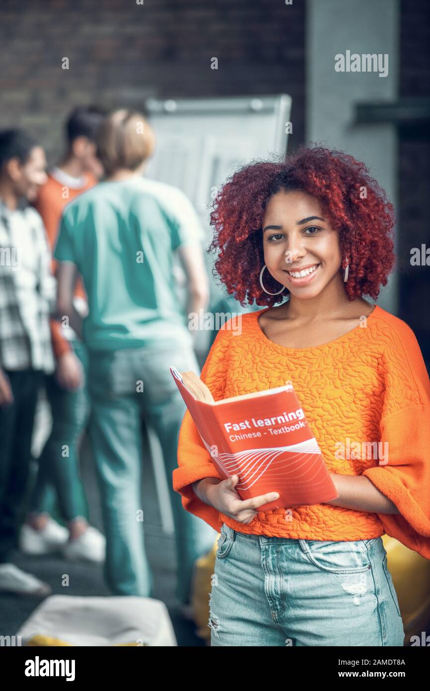 Cheerful red-haired student feeling joyful while studying with friends Stock Photo