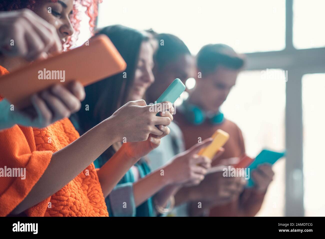 Students holding colorful smartphones while having break from study Stock Photo