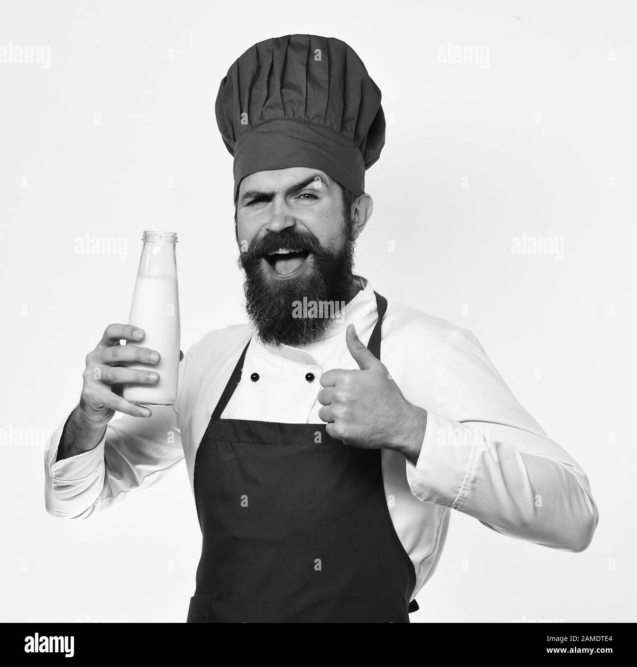 Man with beard holds bottle of milk on white background. Chef with