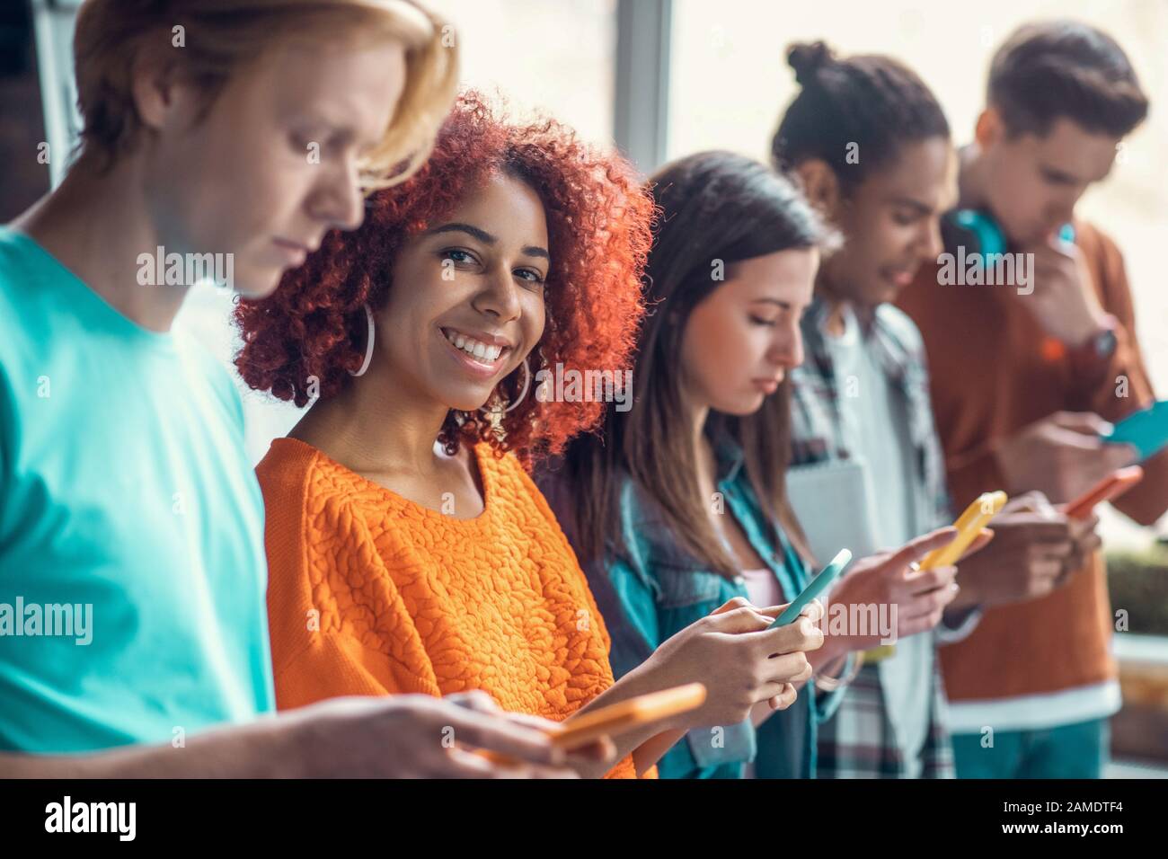 Student smiling standing near friends and using social media Stock Photo