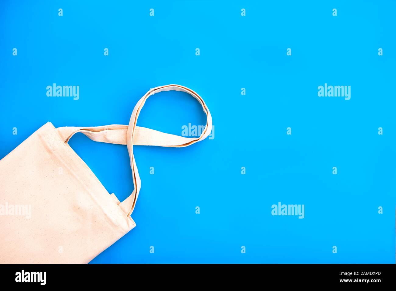 Canvas cotton white bag on the bright blue background. Eco Friendly reusable bag for groceries and shopping. Eco and zero waste concept. Close up. Stock Photo