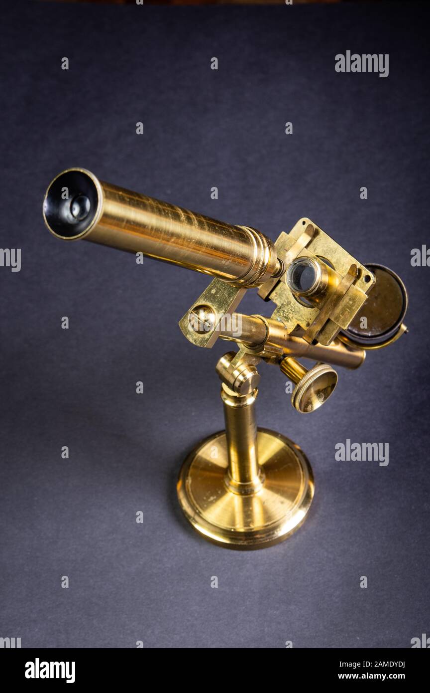 Old brass microscope standing against grey background Stock Photo