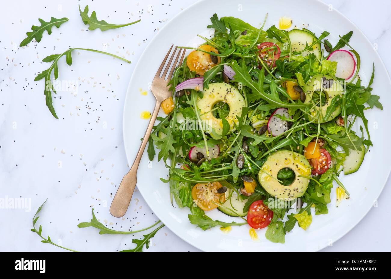 Vegan. Plate of avocado, tomato and rocket salad Stock Photo