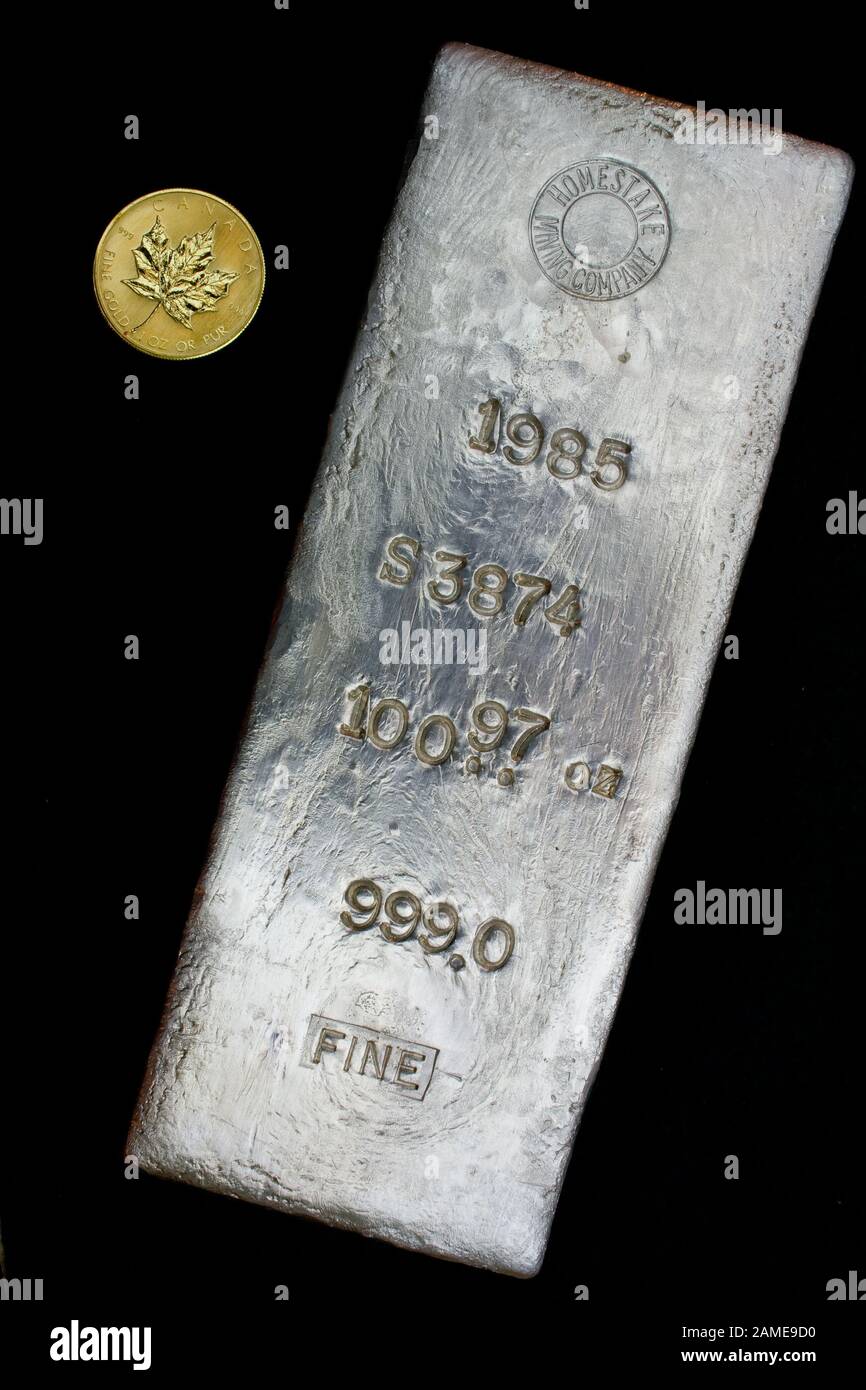 1985 Homestake Mining Company 100.97 troy ounce silver bullion bar poured at Lead, South Dakota - USA. One ounce gold round shown for scale Stock Photo