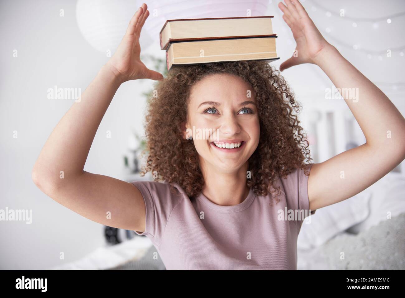 Teenage girl with books on her head Stock Photo - Alamy