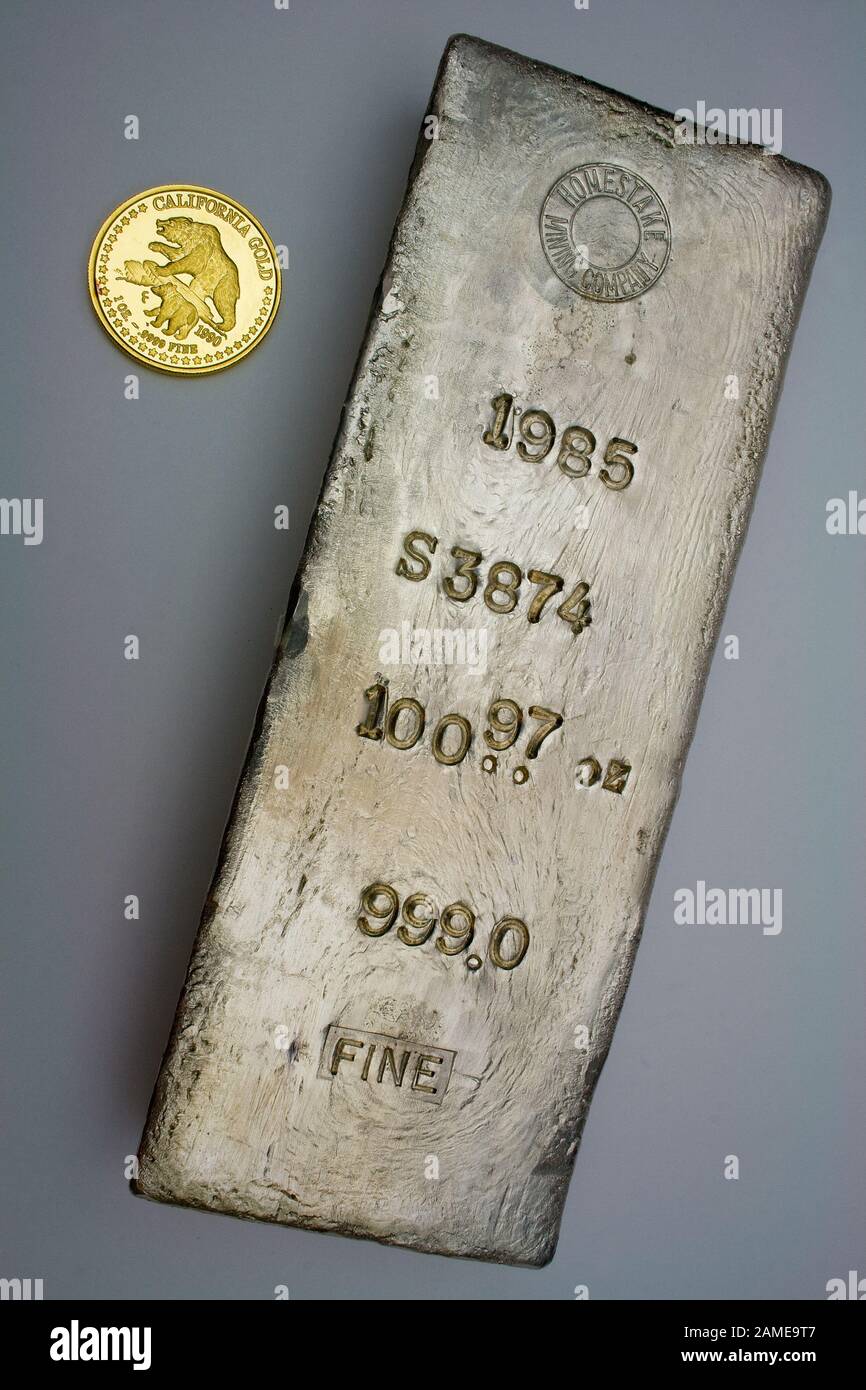 1985 Homestake Mining Company 100.97 troy ounce silver bullion bar poured at Lead, South Dakota - USA. One ounce California gold round shown for scale Stock Photo