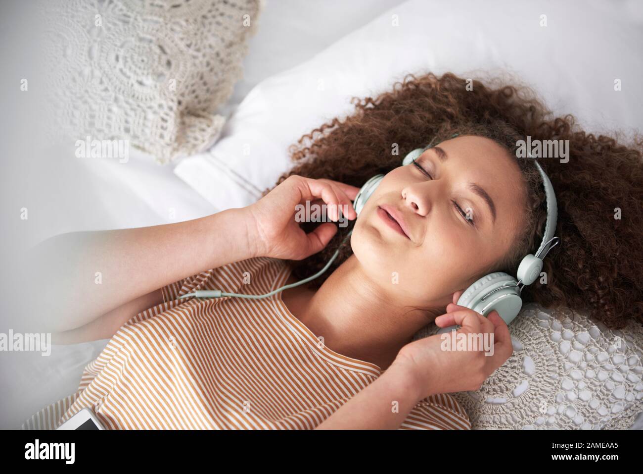 Teenage girl listening to music and lying on the bed Stock Photo - Alamy