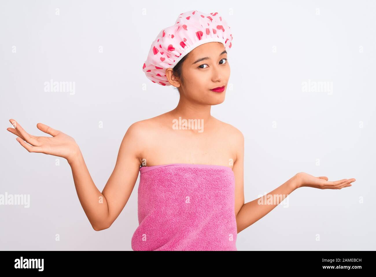 Young chinese woman wearing shower towel and cap bath over isolated ...
