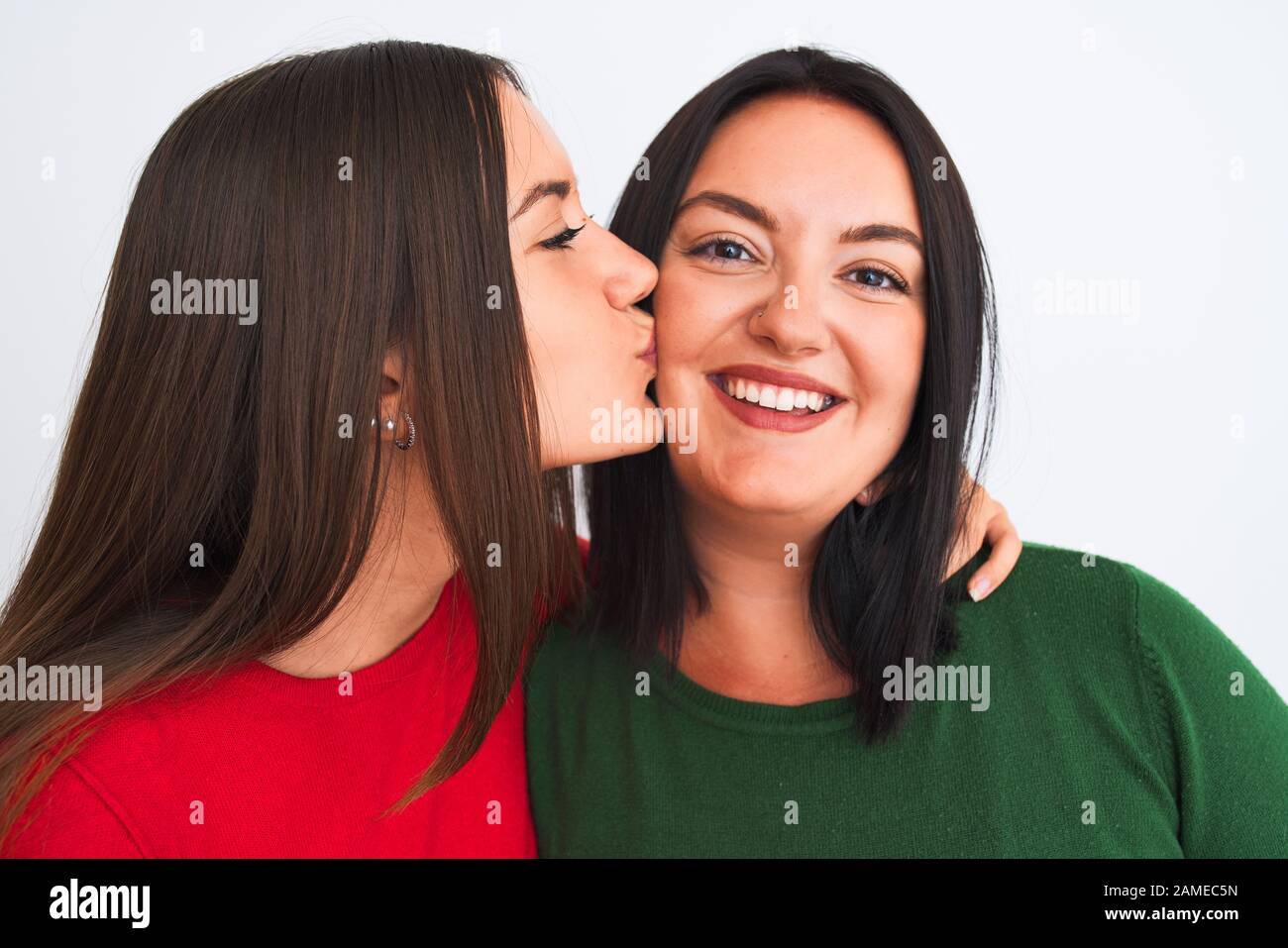 Young beautiful friends smiling happy and confident wearing casual clothes. Standing with a smile on face hugging and kissing over isolated white back Stock Photo