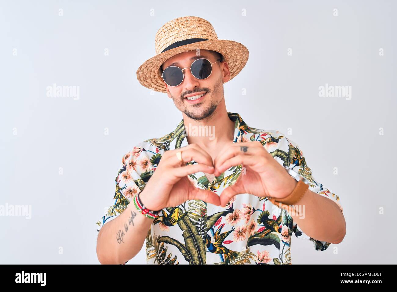 Young handsome man wearing Hawaiian shirt and summer hat over isolated ...