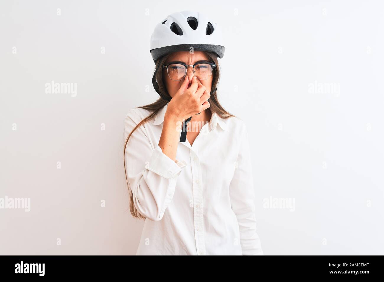 Beautiful businesswoman wearing glasses and bike helmet over isolated white  background smelling something stinky and disgusting, intolerable smell, ho  Stock Photo - Alamy