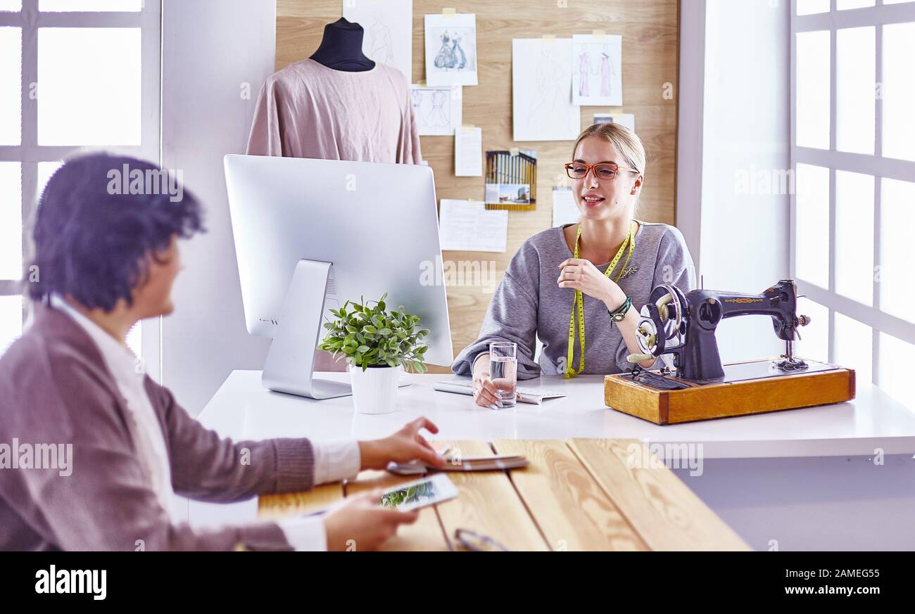 pretty dressmaker showing a new design to her client Stock Photo - Alamy