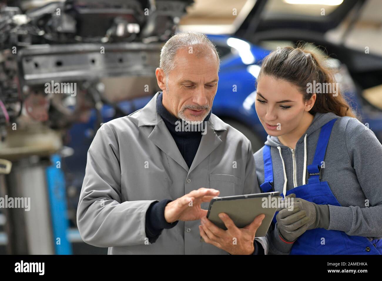 Apprentice with instructor using tablet in workshop Stock Photo