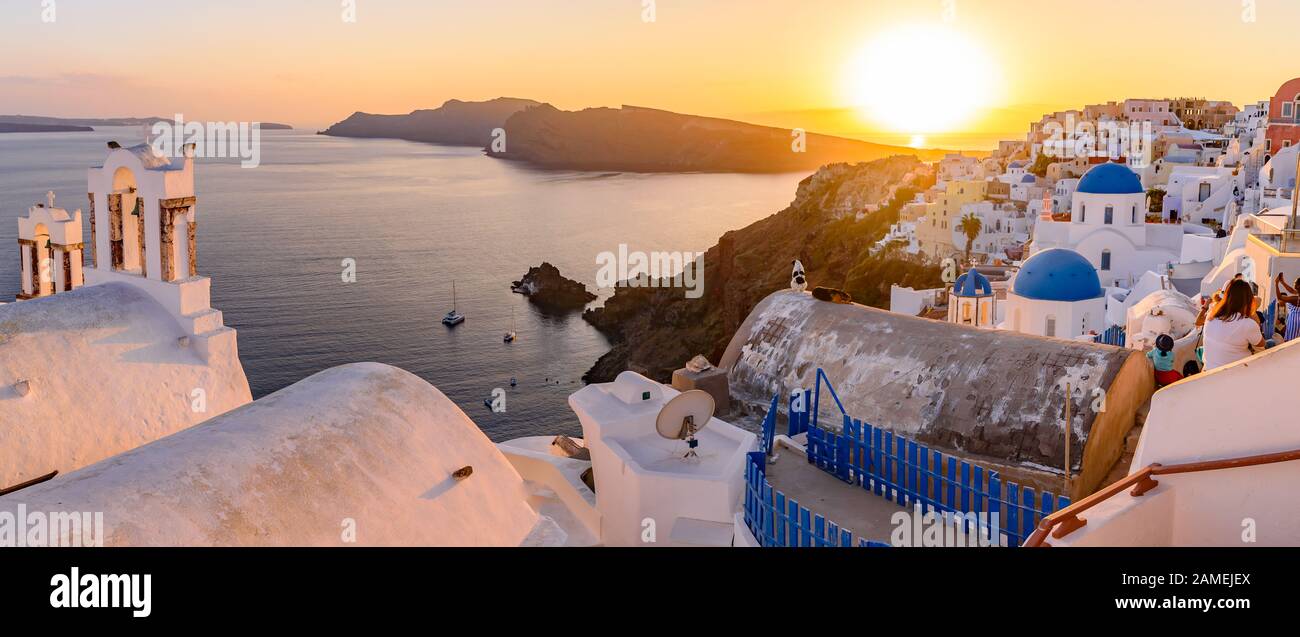 Panoramic view of blue domed churches and bell tower with warm sunset light in Oia, Santorini, Greece Stock Photo