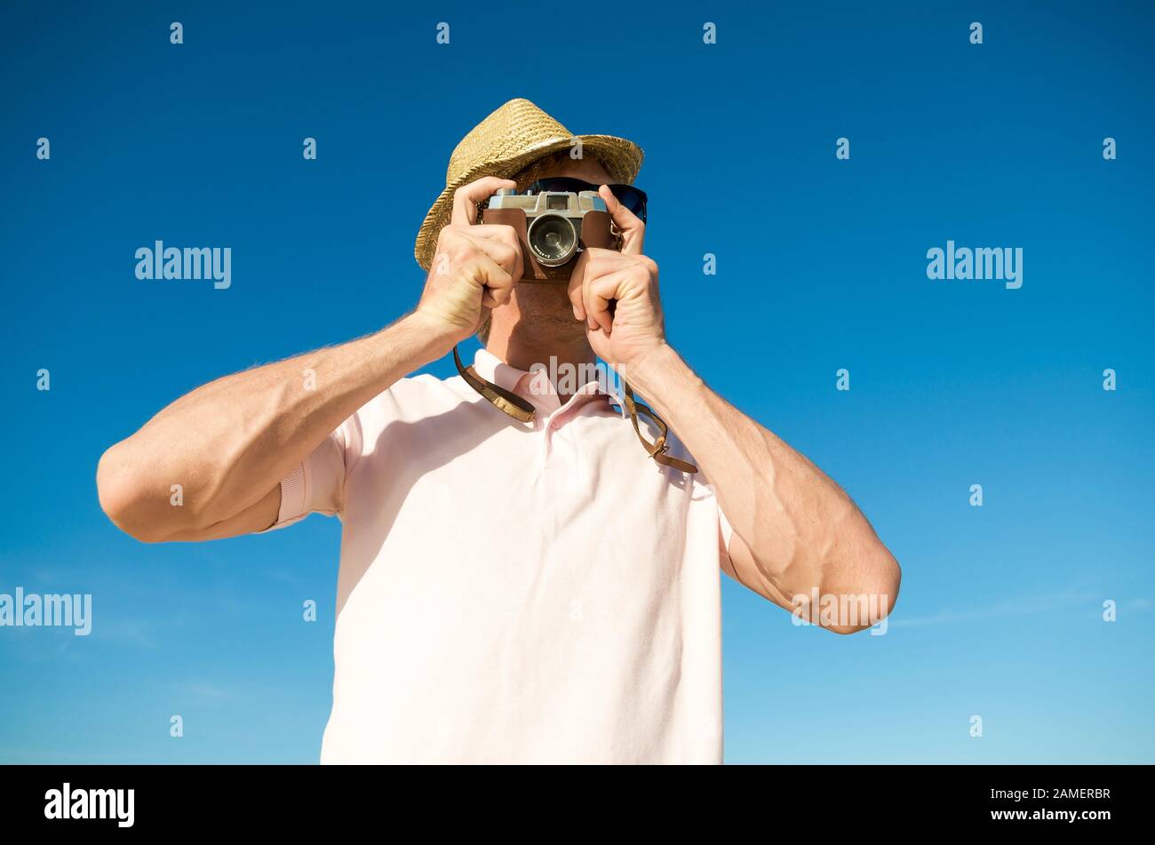 Tourist photographer taking a photo with an old fashioned point and shoot camera in front of bright blue sky copy space Stock Photo
