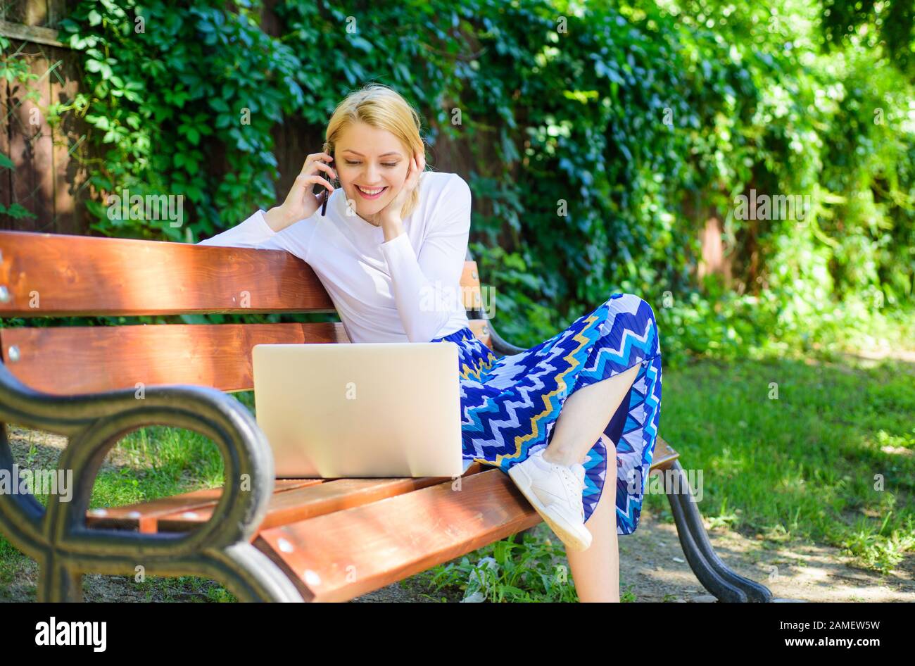 Girl sit bench with notebook call phone. Save your time with shopping online. Shopping online. Woman laptop in park enjoy green nature and fresh air. Girl dreamy takes advantage of online shopping. Stock Photo
