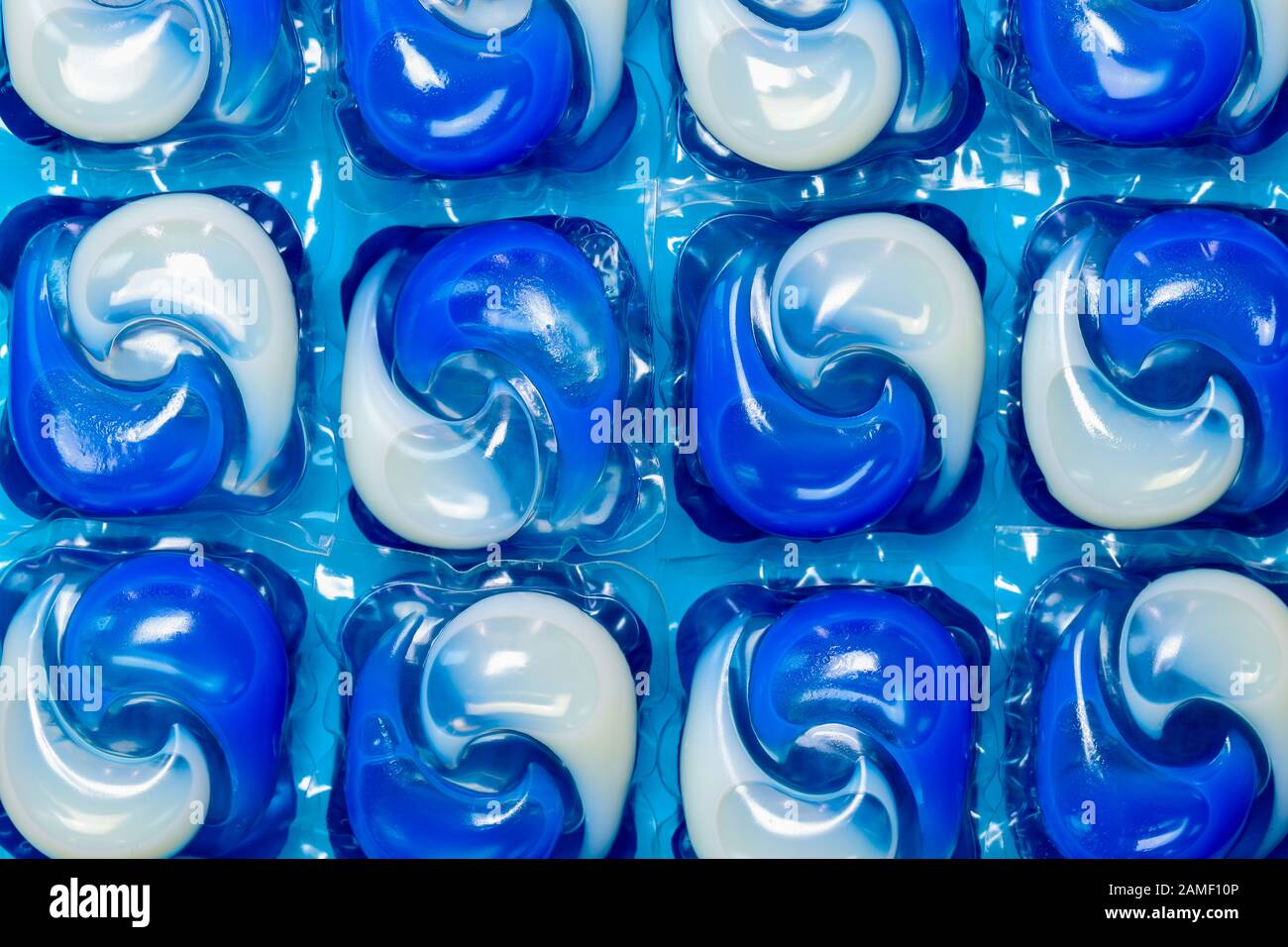 Close up detail of blue and white washing machine liquid detergent laundry capsules/pods isolated against a blue background Stock Photo