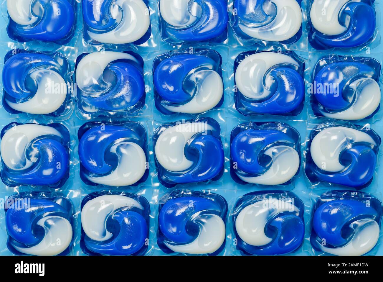 Close up detail of blue and white washing machine liquid detergent laundry capsules/pods isolated against a blue background Stock Photo