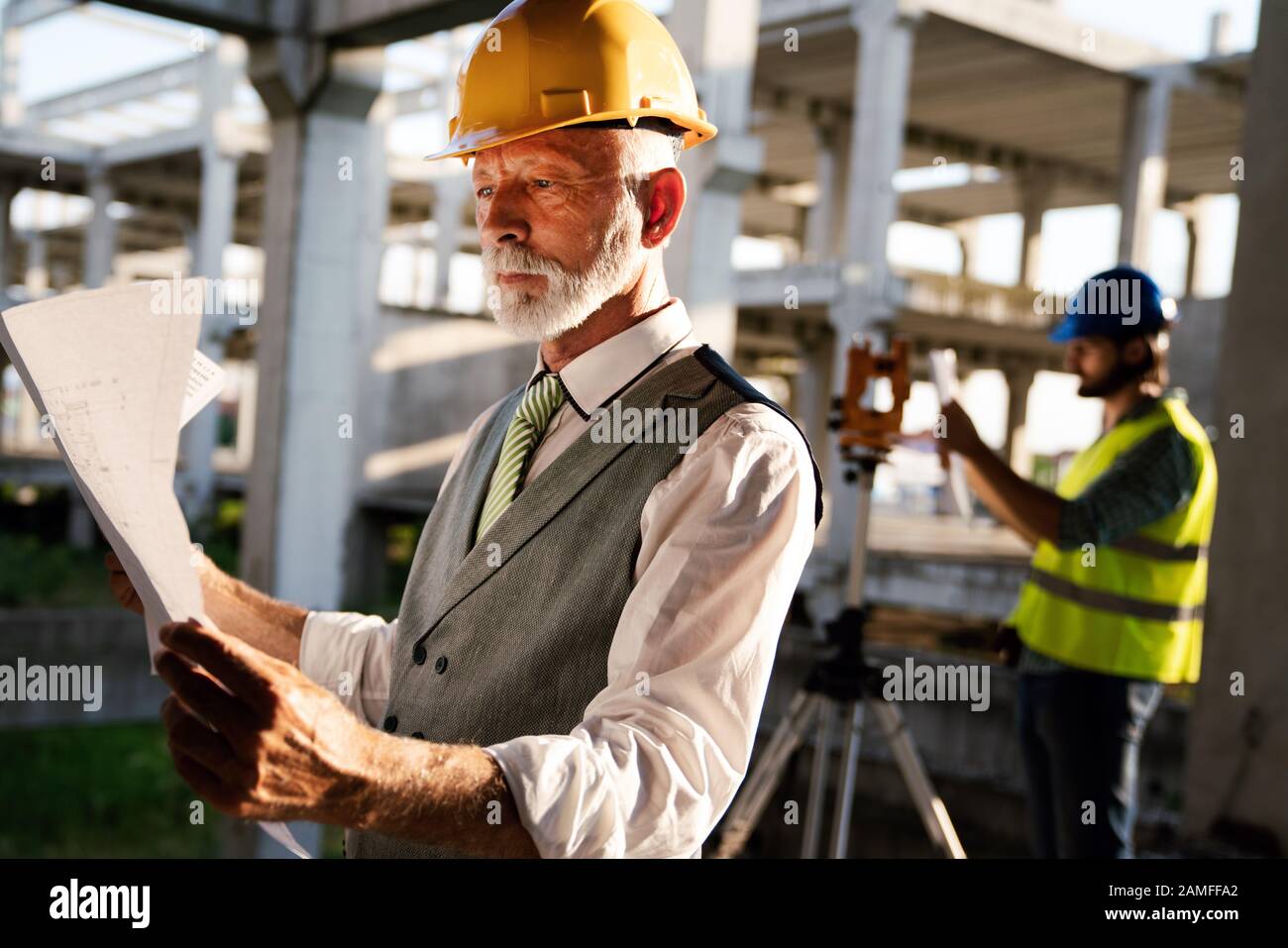 Two satisfied engineers talking at building site with construction structure in background Stock Photo