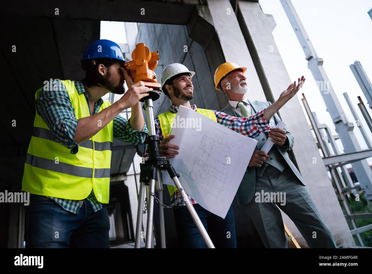 Two satisfied engineers talking at building site with construction structure in background Stock Photo