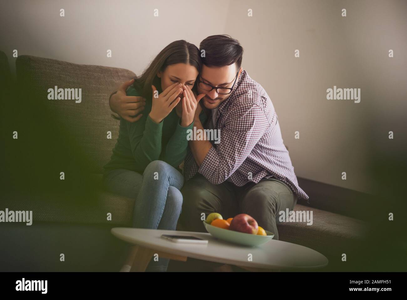 Woman is sad, her man is consoling her. Stock Photo