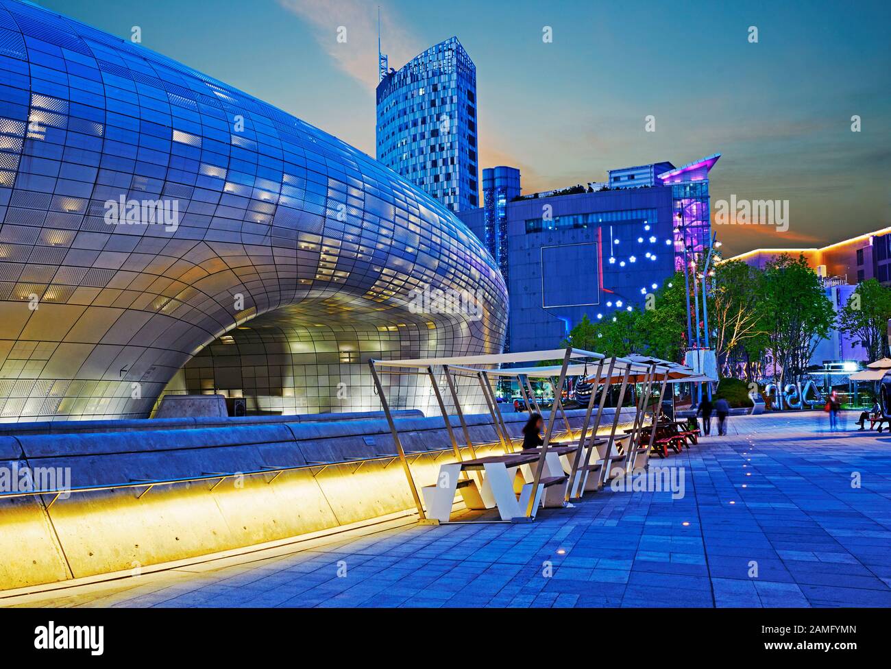 The Dongdaemun Design plaza (designed by Zaha Hadid) and retail district in Seoul illuminated at dusk Stock Photo