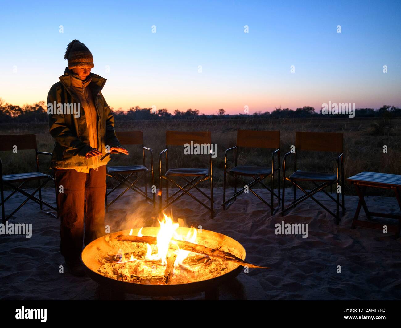 Tourist enjoying the camp fire at Khwai Private Reserve, Okavango Delta, Botswana Stock Photo