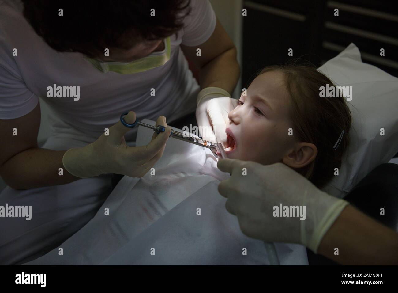 Little girl at dentist office, getting local anesthesia injection into