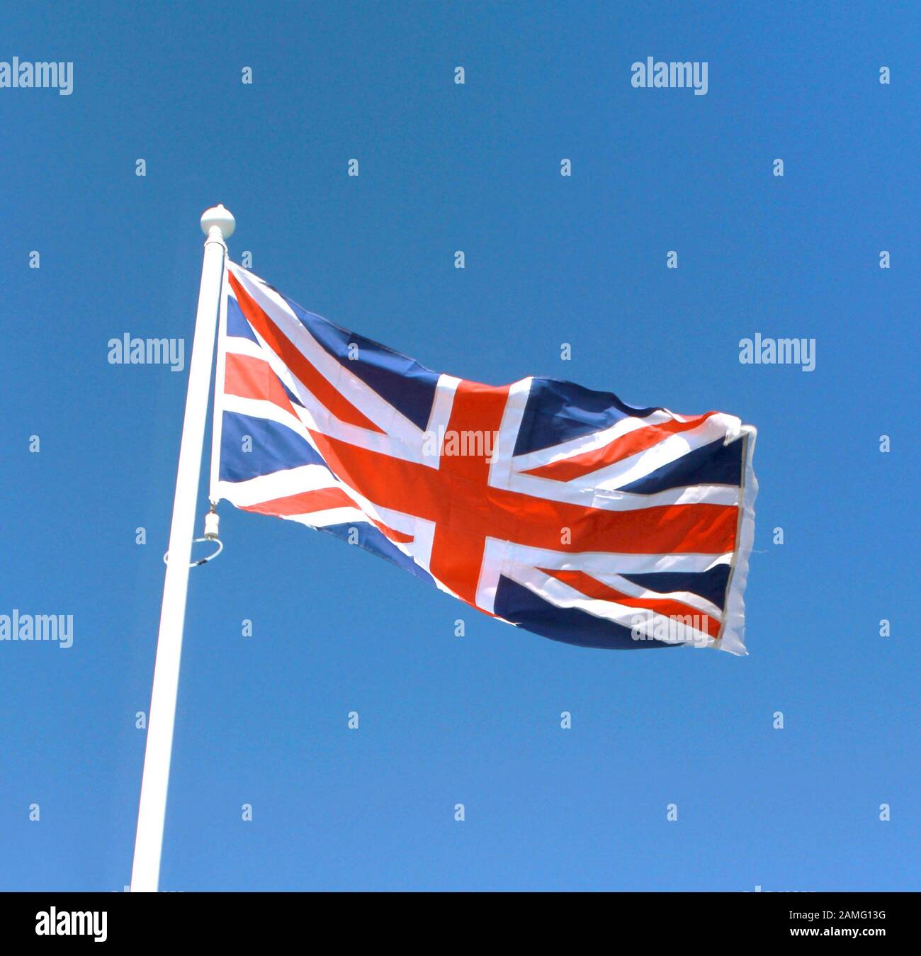Union Jack flag of the United Kingdom flying in a bright blue sky, England. Stock Photo