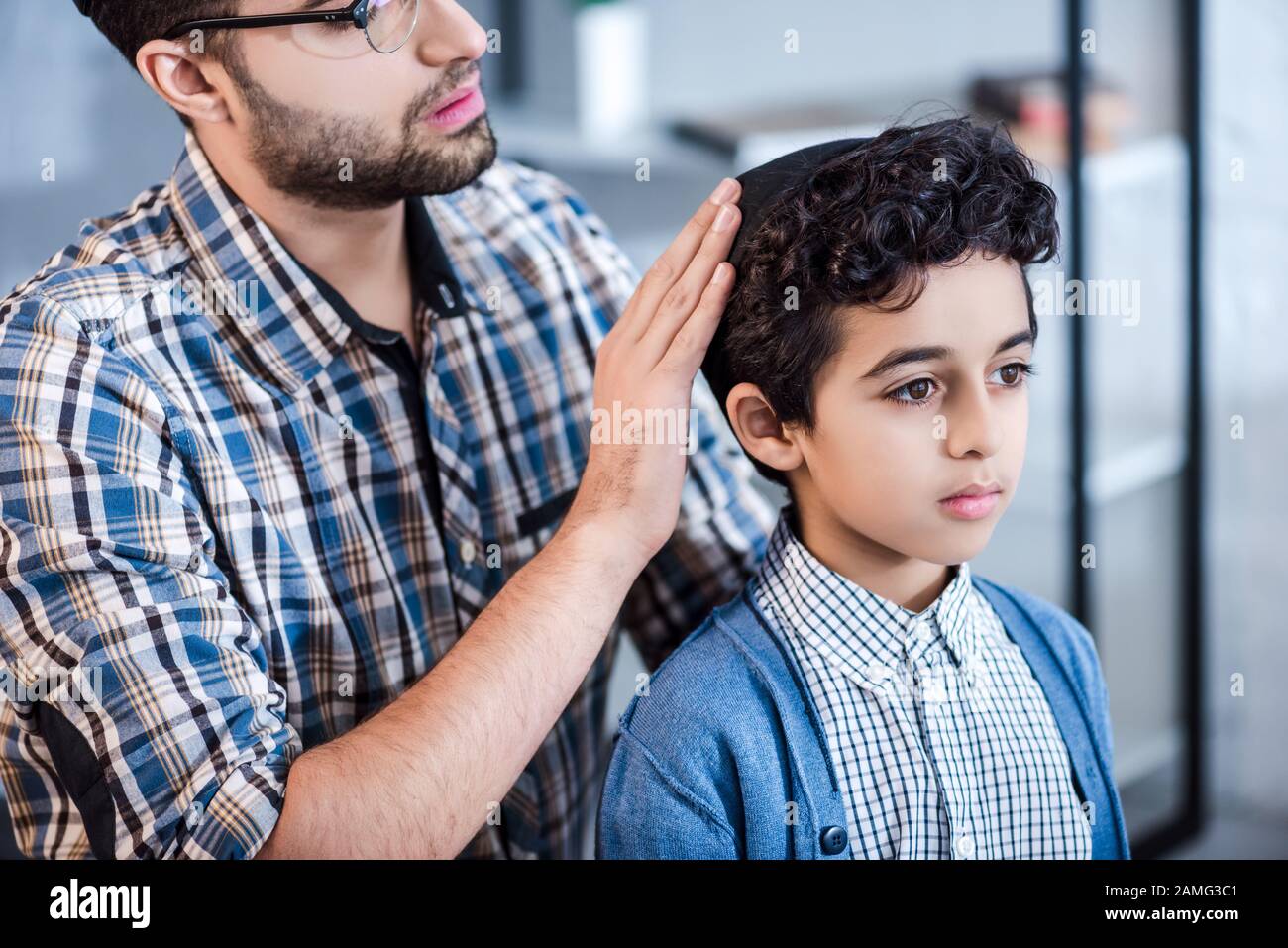 cropped view of jewish father wearing hat on son in apartment Stock Photo