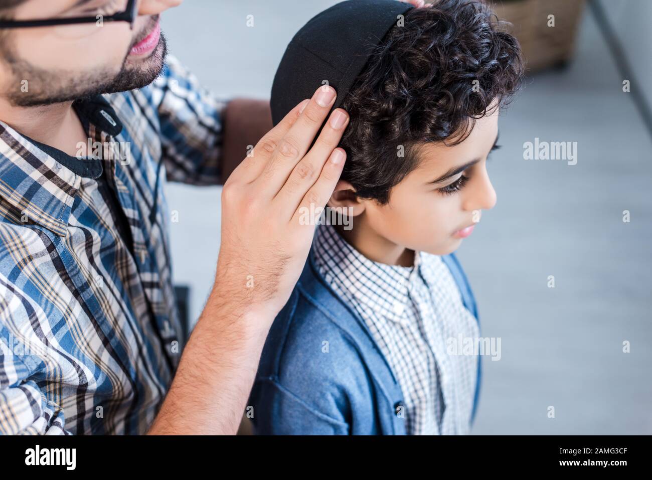 cropped view of jewish father wearing hat on son in apartment Stock Photo
