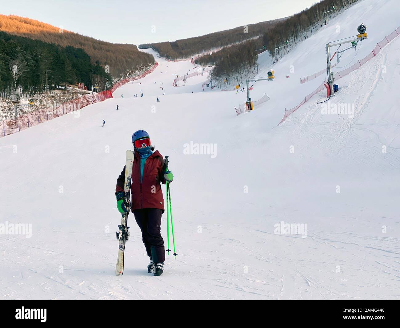 (200113) -- BEIJING, Jan. 13, 2020 (Xinhua) -- Xiao Zhen holding ski boards and poles is seen at a ski field in Chongli district of Zhangjiakou city, north China's Hebei Province, Jan. 12, 2020. Xiao Zhen, a staff of a Beijing's internet company, has been keen on skiing for four years and always goes to the ski fields in Chongli district of Zhangjiakou city in north China's Hebei province. According to Xiao, She used to spend four to five hours thumbing a lift or taking a bus to Chongli from Beijing. The recent operation of the Beijing-Zhangjiakou high-speed railway line reduced the travel tim Stock Photo