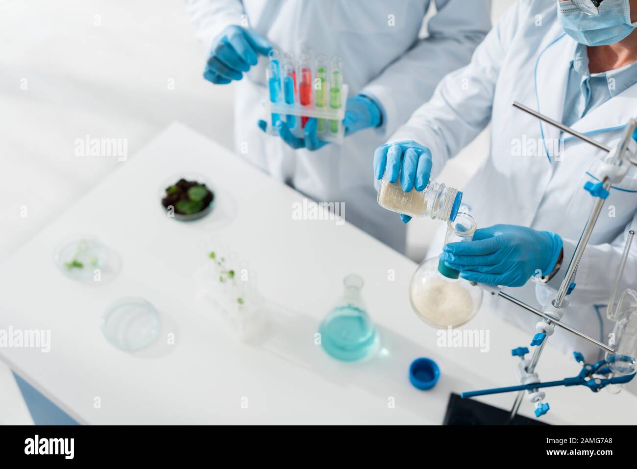 cropped view of biologists in white coats doing test in lab Stock Photo
