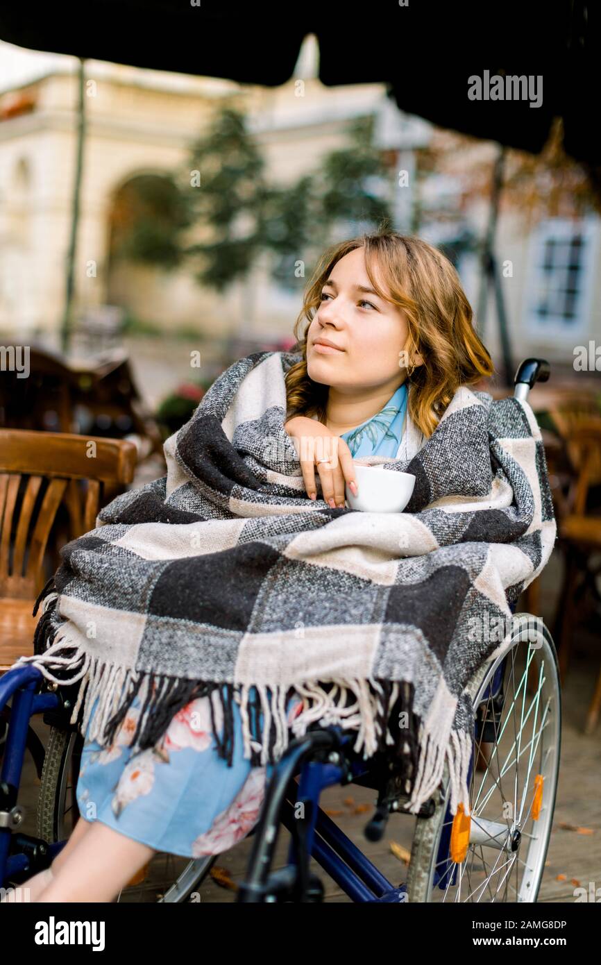 Portrait of a pretty young woman in a wheelchair enjoying her day and ...