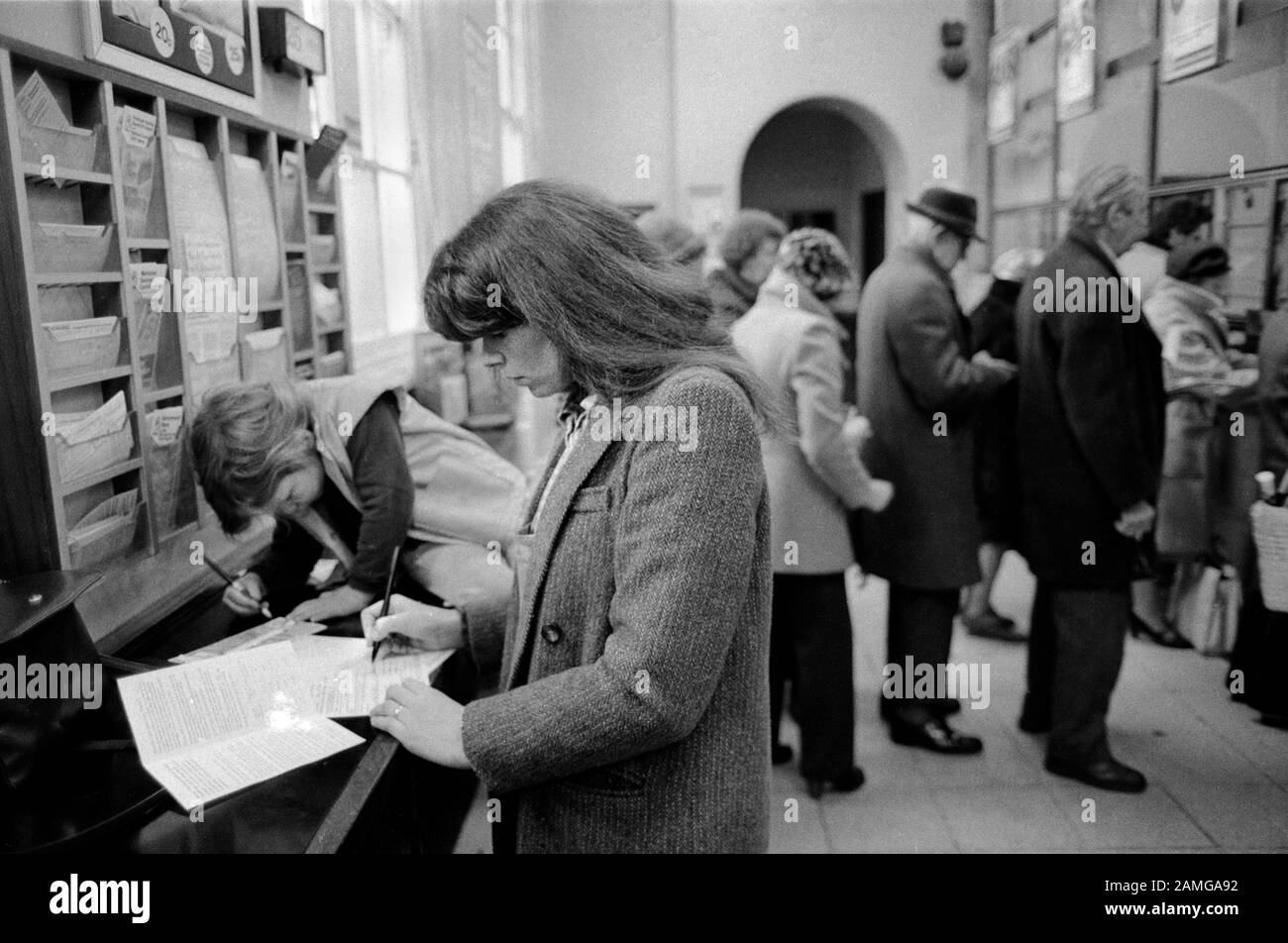 Post Office 1980s London UK. People filling in forms selecting leaflets. Mother and child going to the Post Office 1981 HOMER SYKES Stock Photo