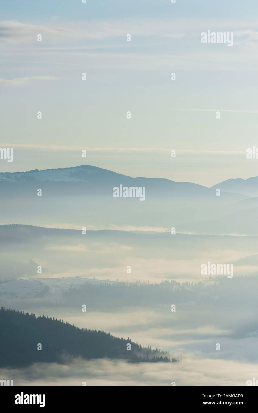 scenic view of snowy mountains with pine trees in white fluffy clouds ...