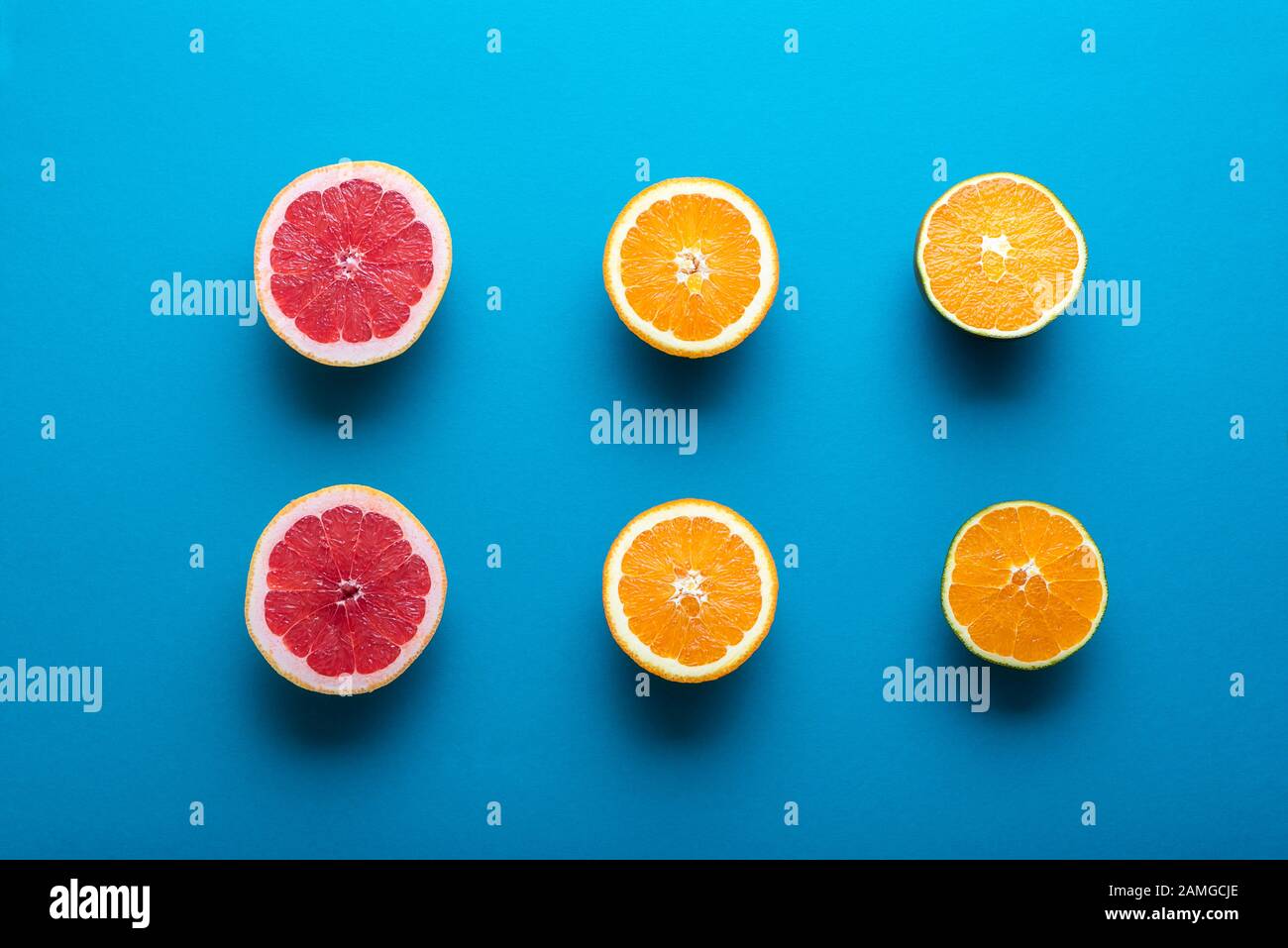 Fresh citrus fruits cut in half on blue background. Above view of
