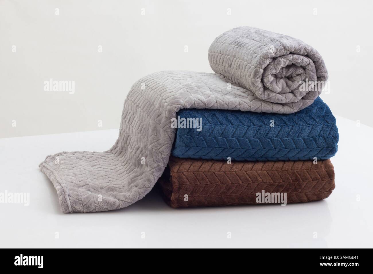 stack of folded soft blankets on the white table Stock Photo