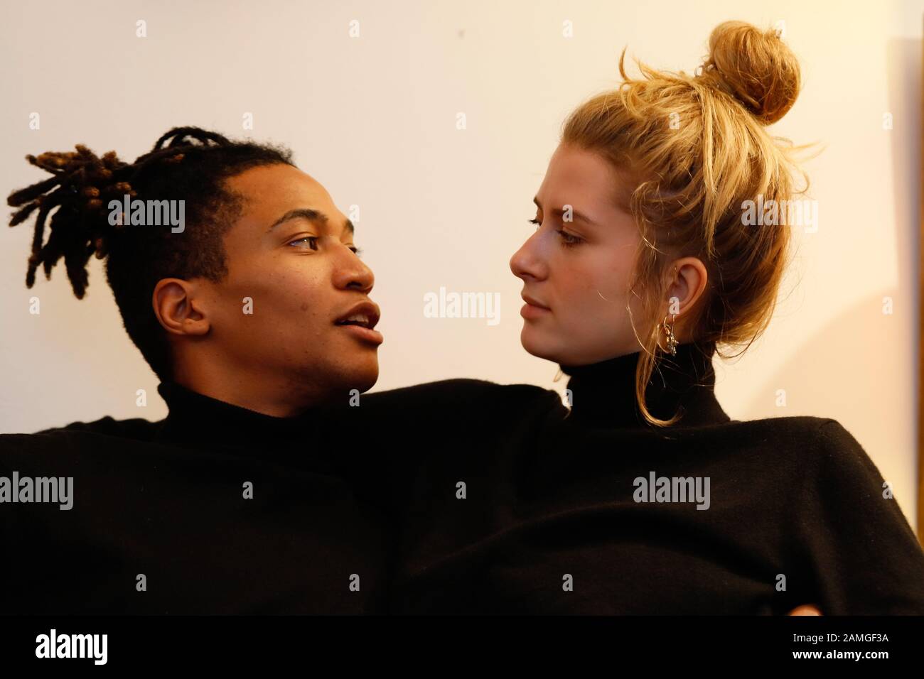 Young intercultural caucasian-hispanic student couple posing on sofa. Stock Photo
