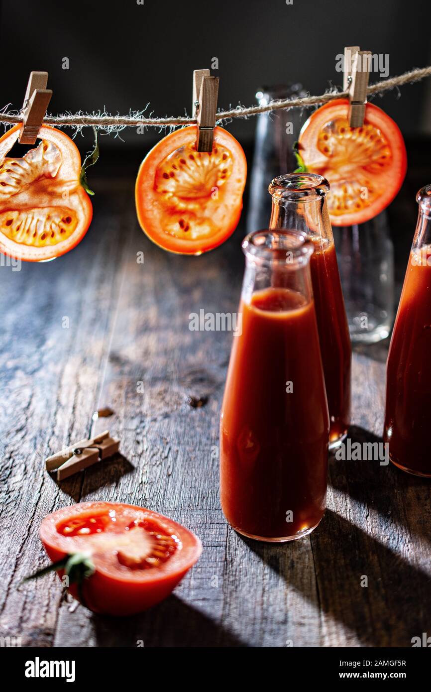 Tomato slices hung on a string.Tomato juice in glass bottles.Fresh drink and food. Stock Photo