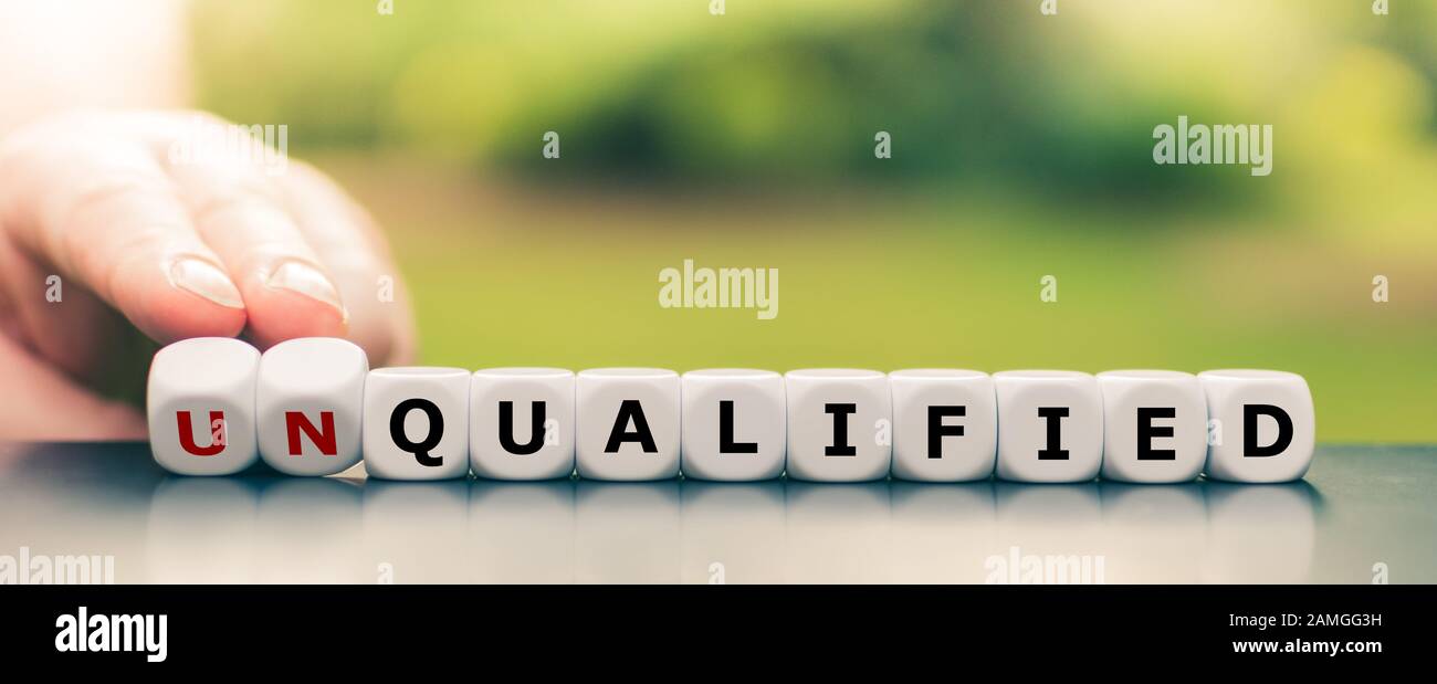 Hand turns dice and changes the word unqualified to qualified. Stock Photo