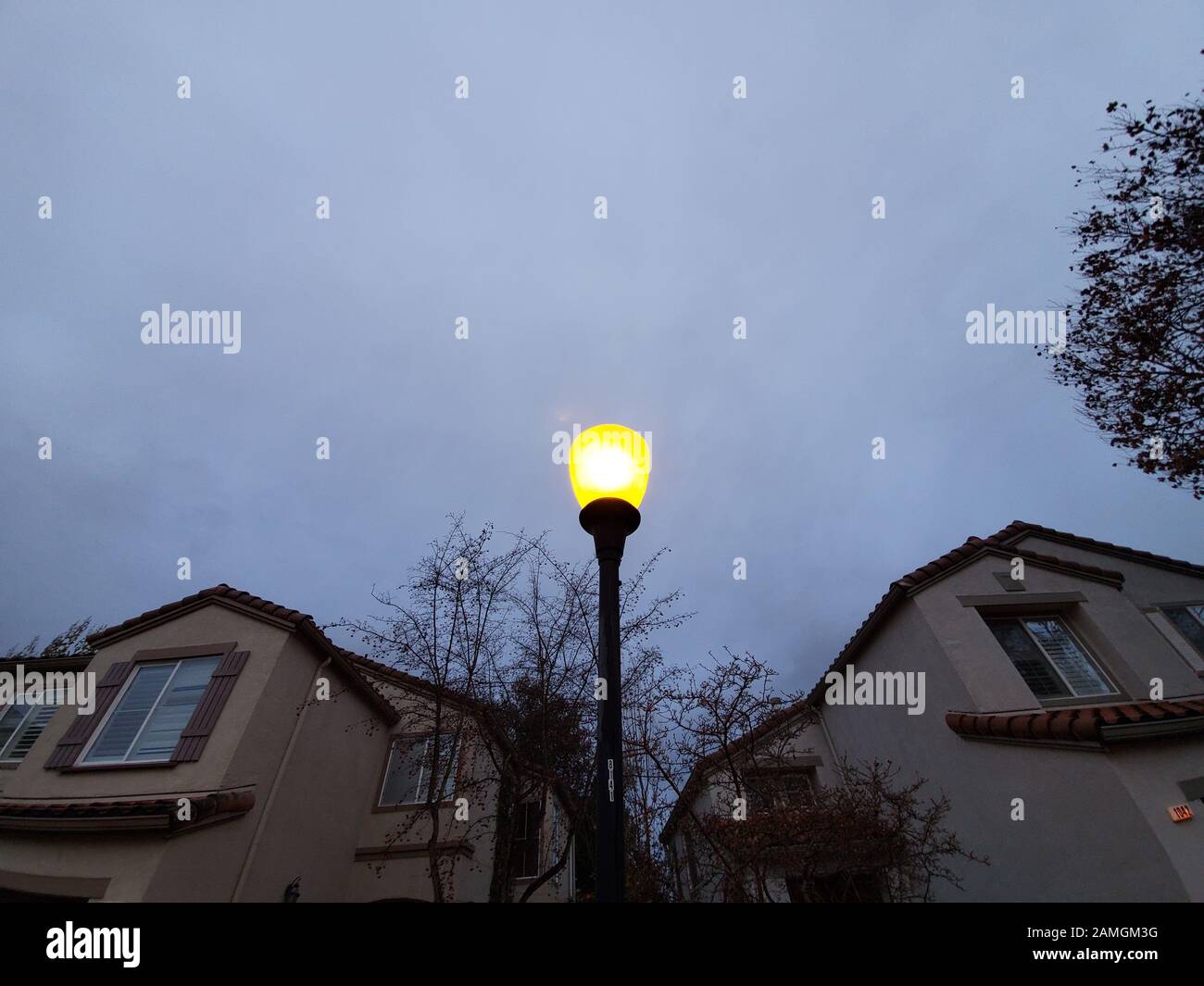 Close-up up top of street lamp, showing typical orange glow of a sodium vapor light, San Ramon, California, December 18, 2019. As more areas switch to LED street lighting, the color temperature of nightime lights is increasing, from the dark yellow of sodium vapor lamps to the bright white of LEDs. () Stock Photo