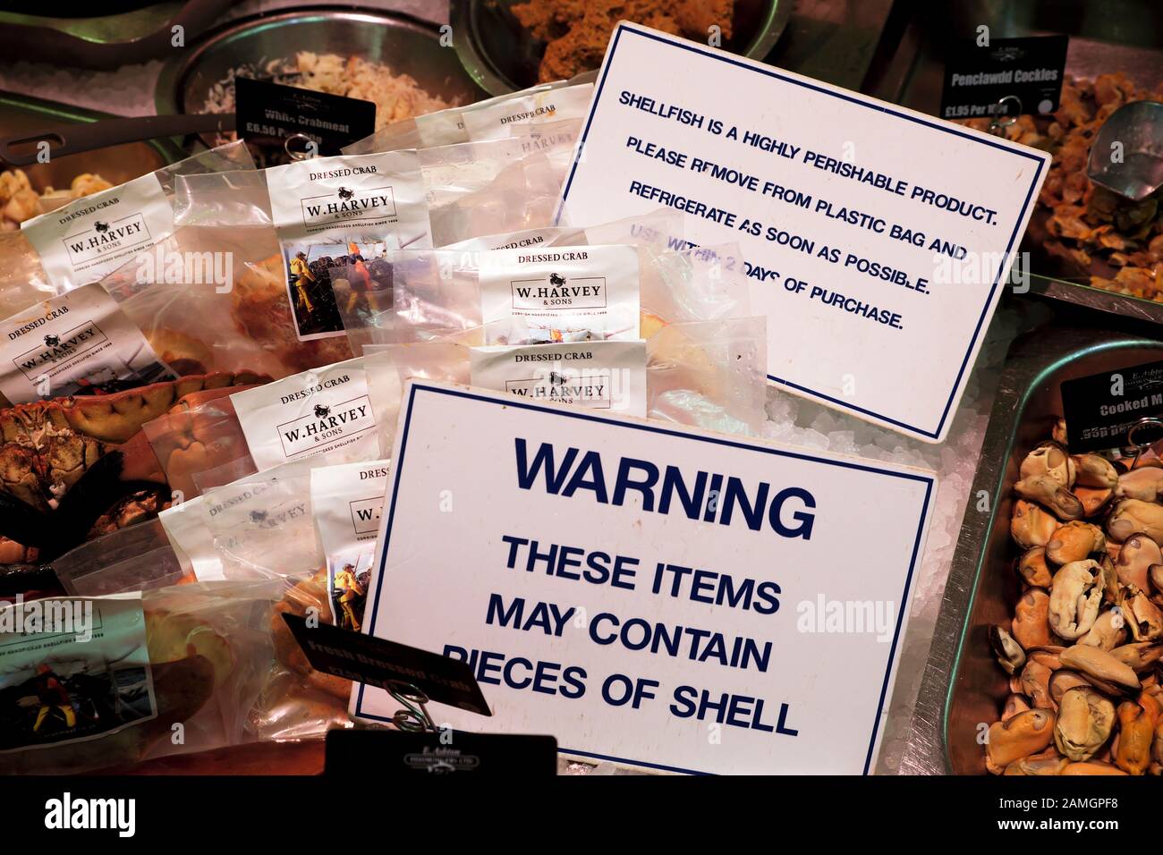 'Warning these items may contain pieces of shell' sign in refrigerated display on Ashton seafood stall in Cardiff Market in Wales UK  KATHY DEWITT Stock Photo