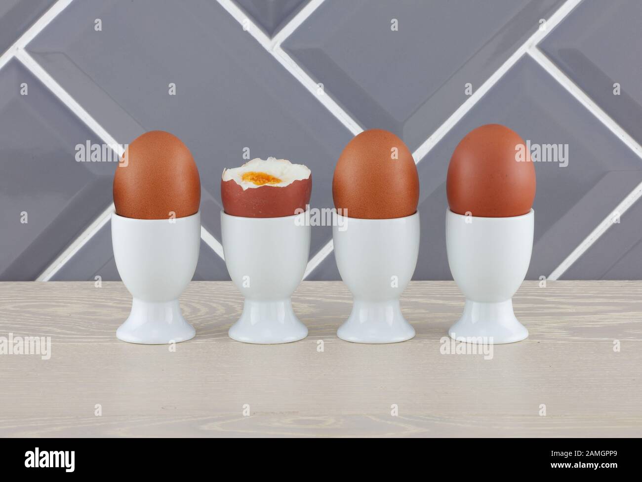 Four eggs in eggcups on wooden kitchen surface Stock Photo