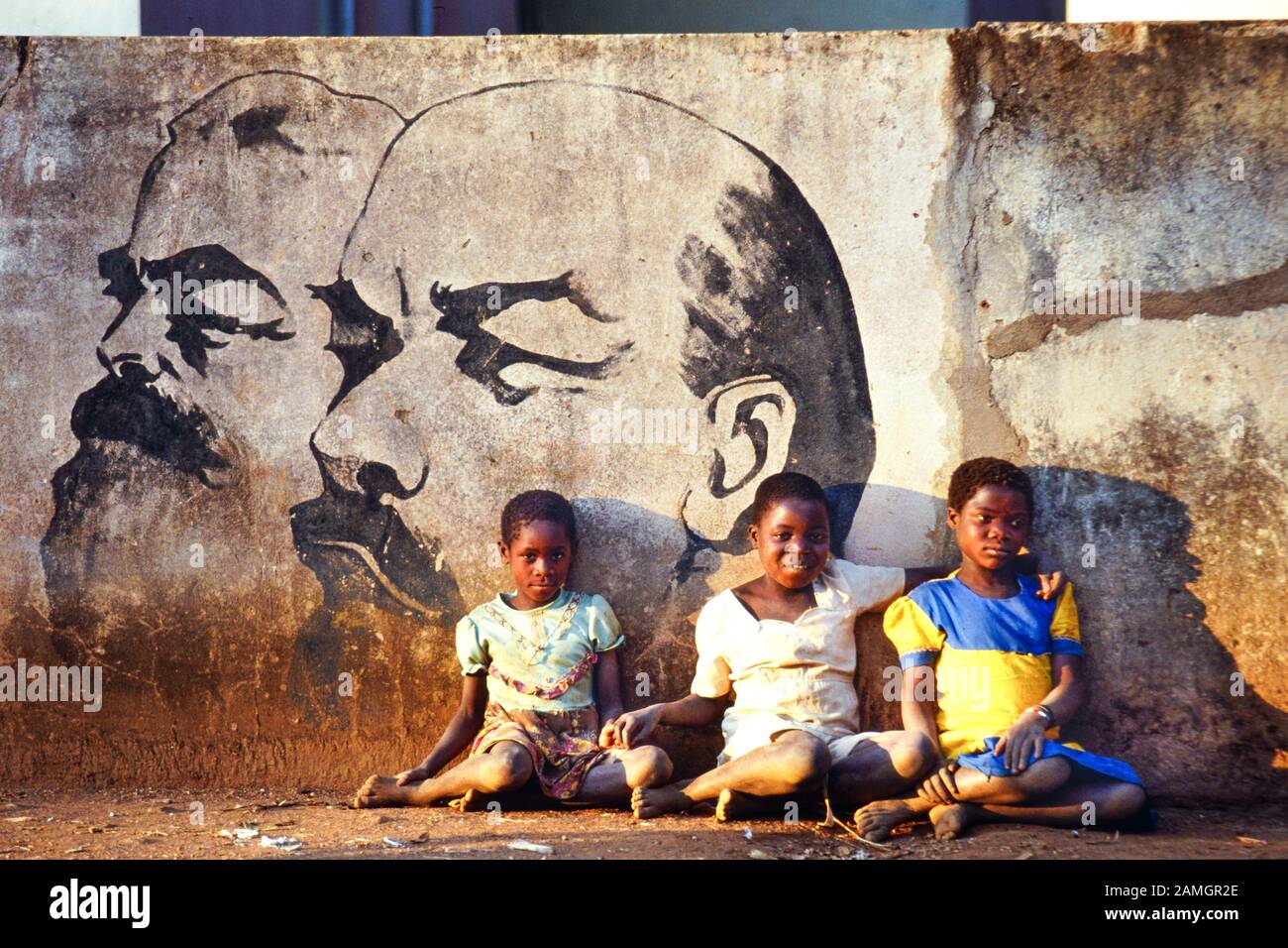 Vintage photo 35mm slide from 1993: african girls sit in front of a wall picture which shows the communist leaders Marx and Lenin. Quelimane village in Tete province, Mozambique, Africa Stock Photo