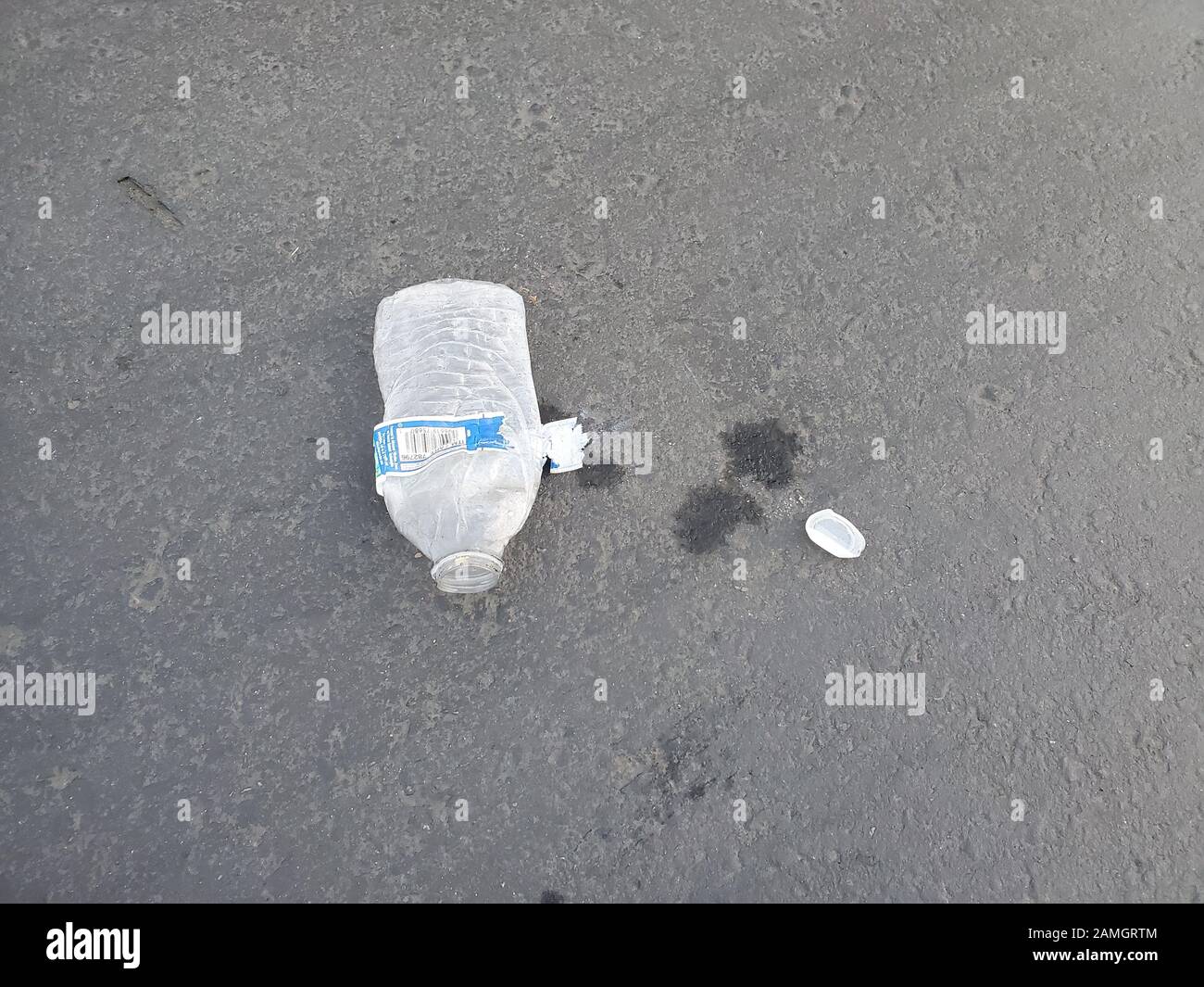 Close-up of crushed plastic water bottle on road surface, an example of plastic litter pollution, San Ramon, California, January 3, 2020. An increasing public awareness of ocean pollution by plastic waste has led to efforts to reduce single use plastics including water bottles. () Stock Photo