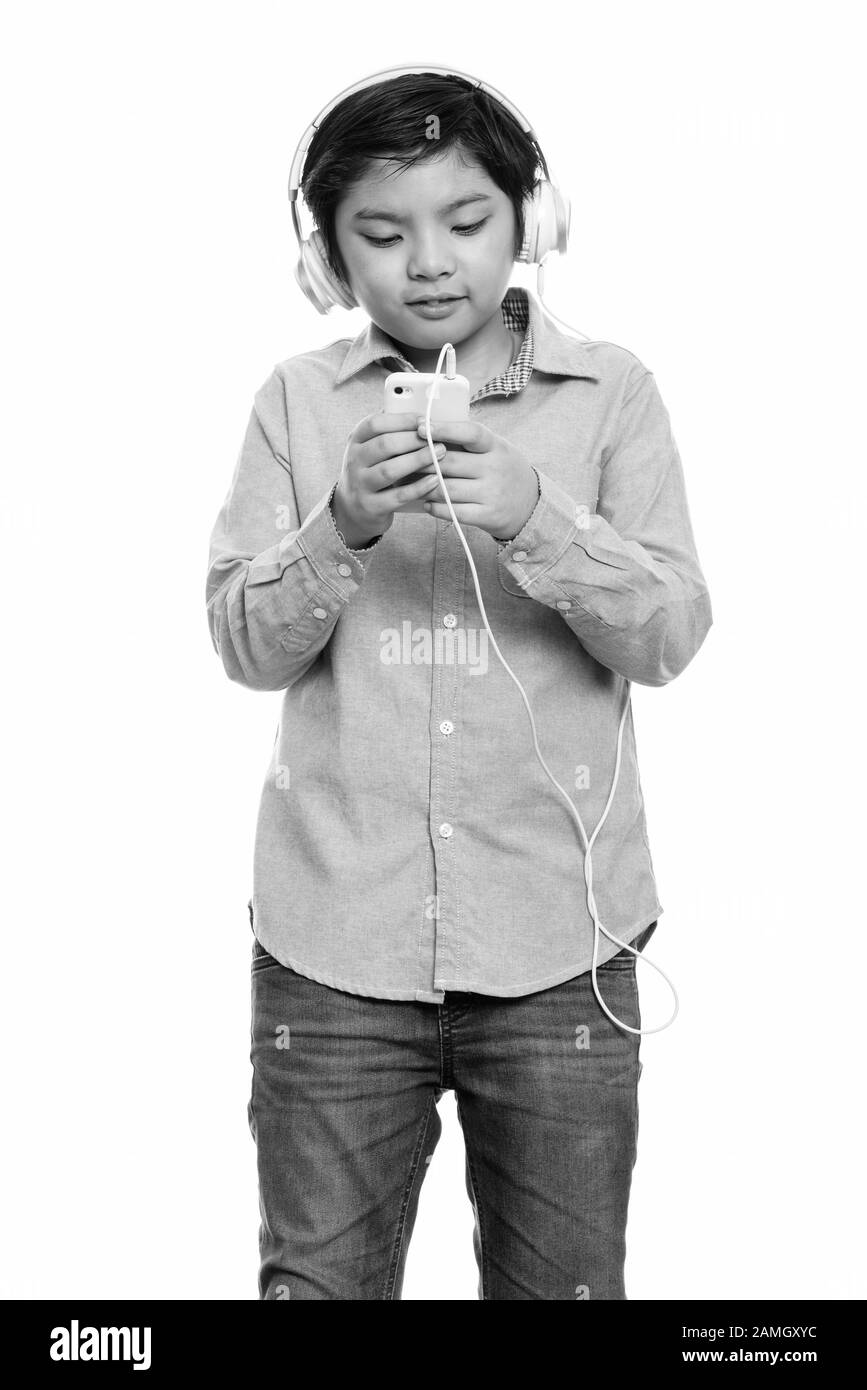 Cute Japanese boy listening to music while using mobile phone Stock Photo