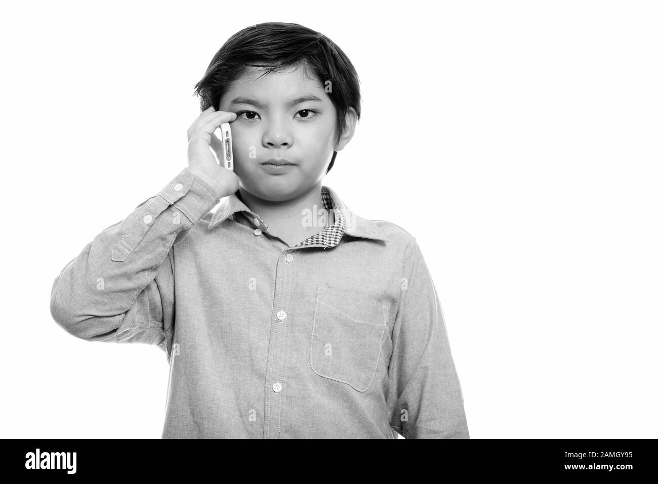 Studio shot of cute Japanese boy talking on mobile phone Stock Photo